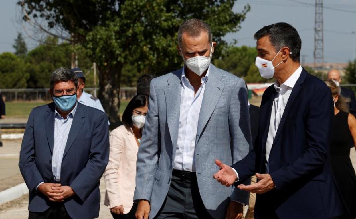 El rey Felipe VI y el presidente del Gobierno, Pedro Sánchez, conversan durante su visita este sábado al centro de acogida temporal instalado en la base de Torrejón.