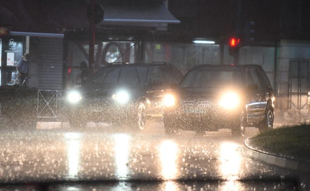 Dos coches circulan por Valladolid capital en pleno chaparrón durante la tarde de este martes.