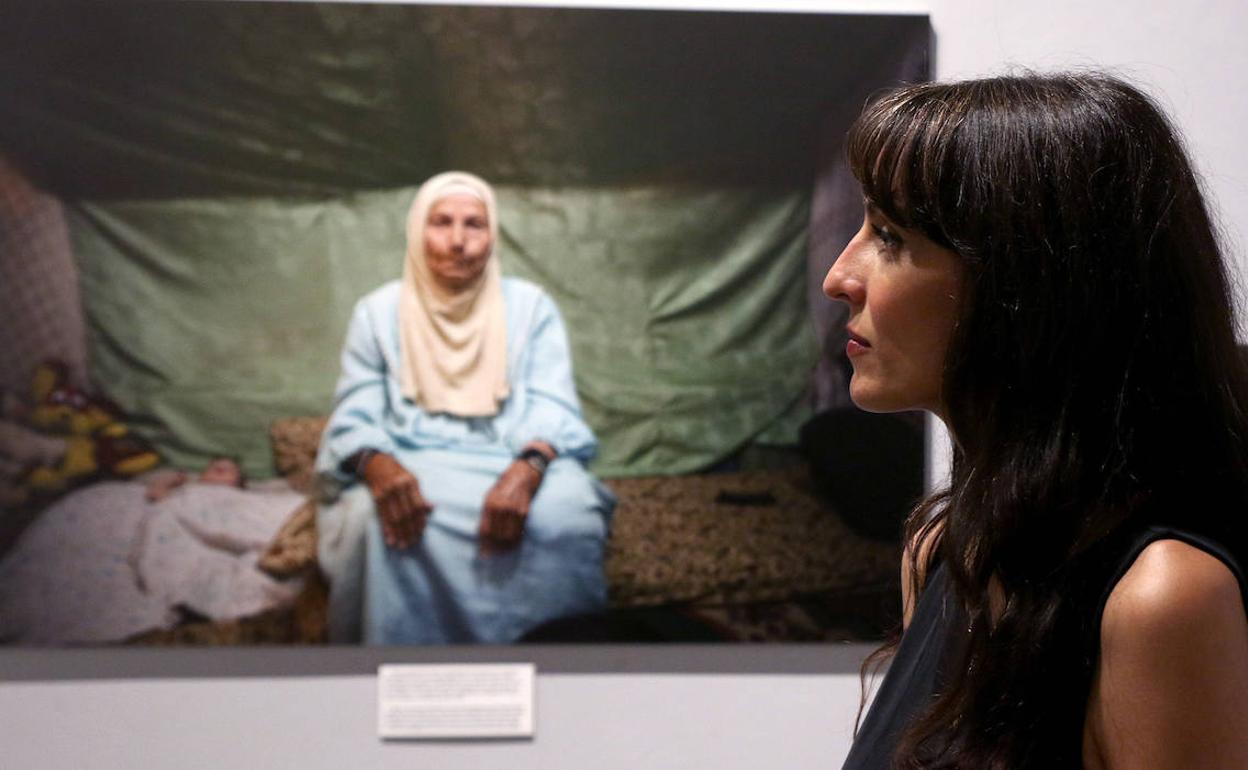 La fotoperiodista Maysun, junto a una de sus fotografías expuestas en La Alhóndiga.