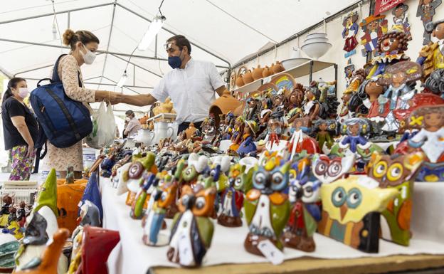 Una mujer comprar un producto en la feria de artesania.