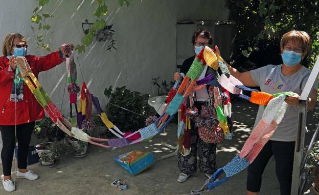 Tres mujeres enseñan el decorado de ganchillo que realizaron para adornar el pueblo.