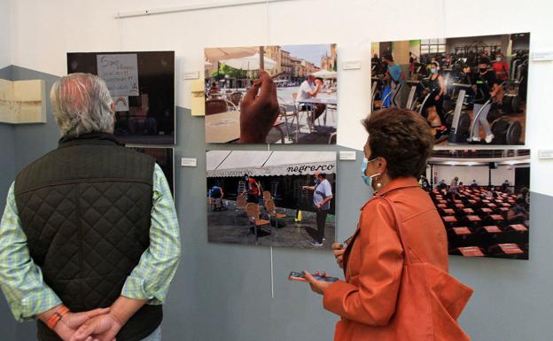 Dos invitados a la inauguración contemplan varias fotografías.