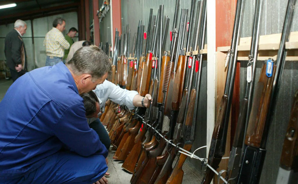 Varias personas examinan armas sacadas a subasta en la Comandancia de la Guardia Civil. 
