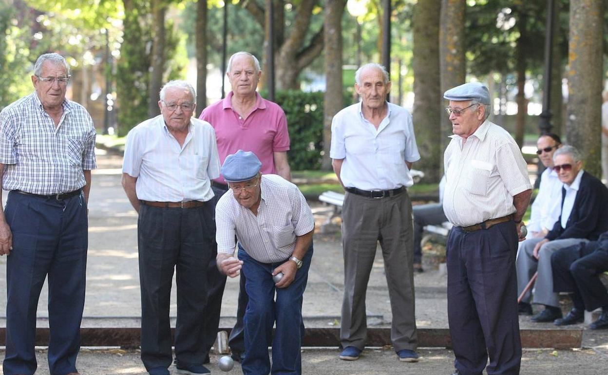 Varias personas juegan a la petanca. 