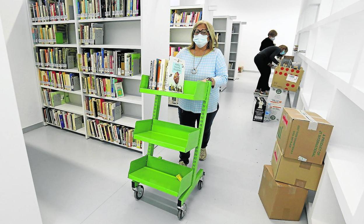 Trabajadoras del departamento de Cultura del Ayuntamiento colocan los libros en las nuevas instalaciones de la biblioteca