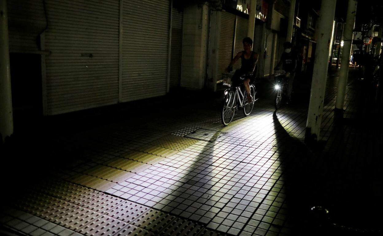 Dos personas alumbran con sus bicicletas una calle japonesa durante un apagón en septiembre. 