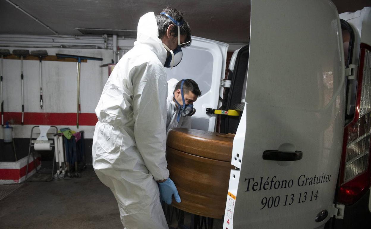Los servicios funerarios intorducen un féretro en una furgoneta para su traslado al tanatorio durante la pandemia. 