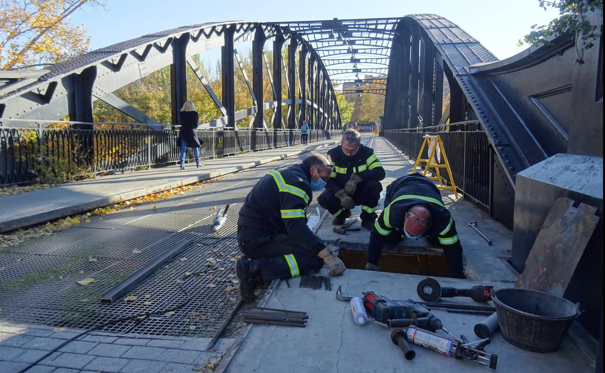 Los operarios reparan el primer tramo de la acera del puente. 