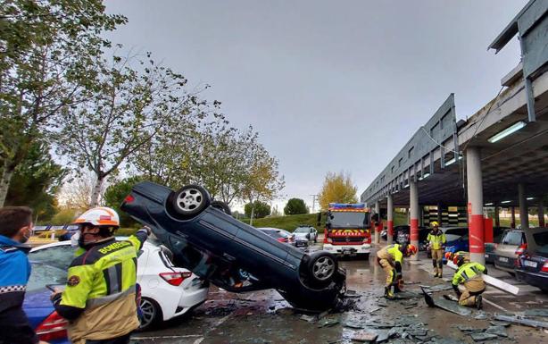 Los Bomberos despejan la calzada de los restos de la valla de pizarra derribada por el coche siniestrado. 