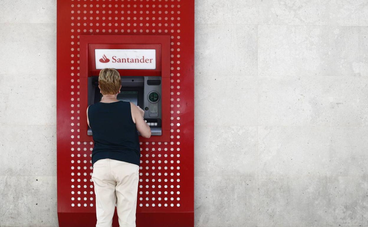 Una mujer saca dinero en un cajero del Banco Santander. 