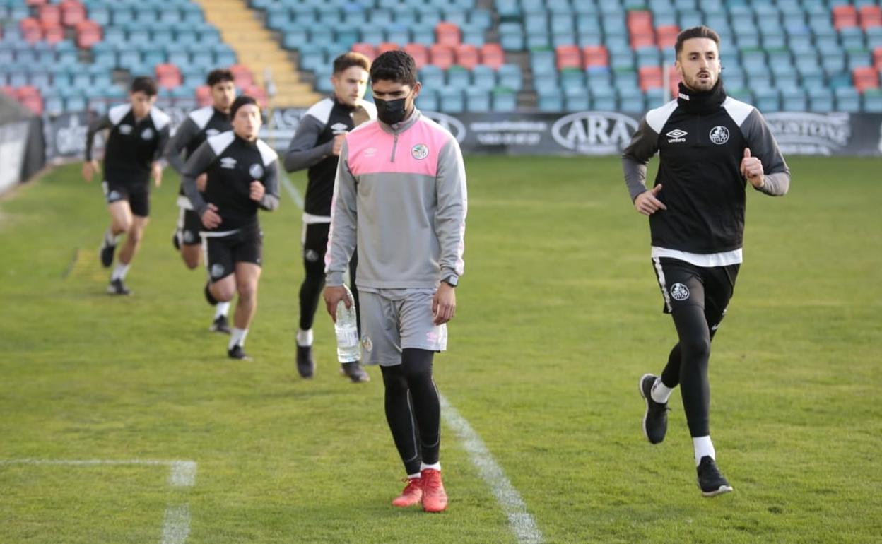 Luis Martínez, esta tarde con mascarilla, se retira del campo mientras sus compañeros realizan carrera continua. 