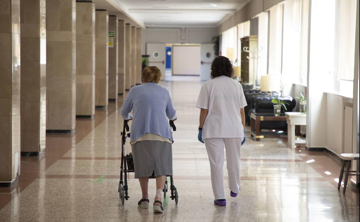 Una cuidadora acompaña a una residente en las dependencias de Doctor Villacián. 