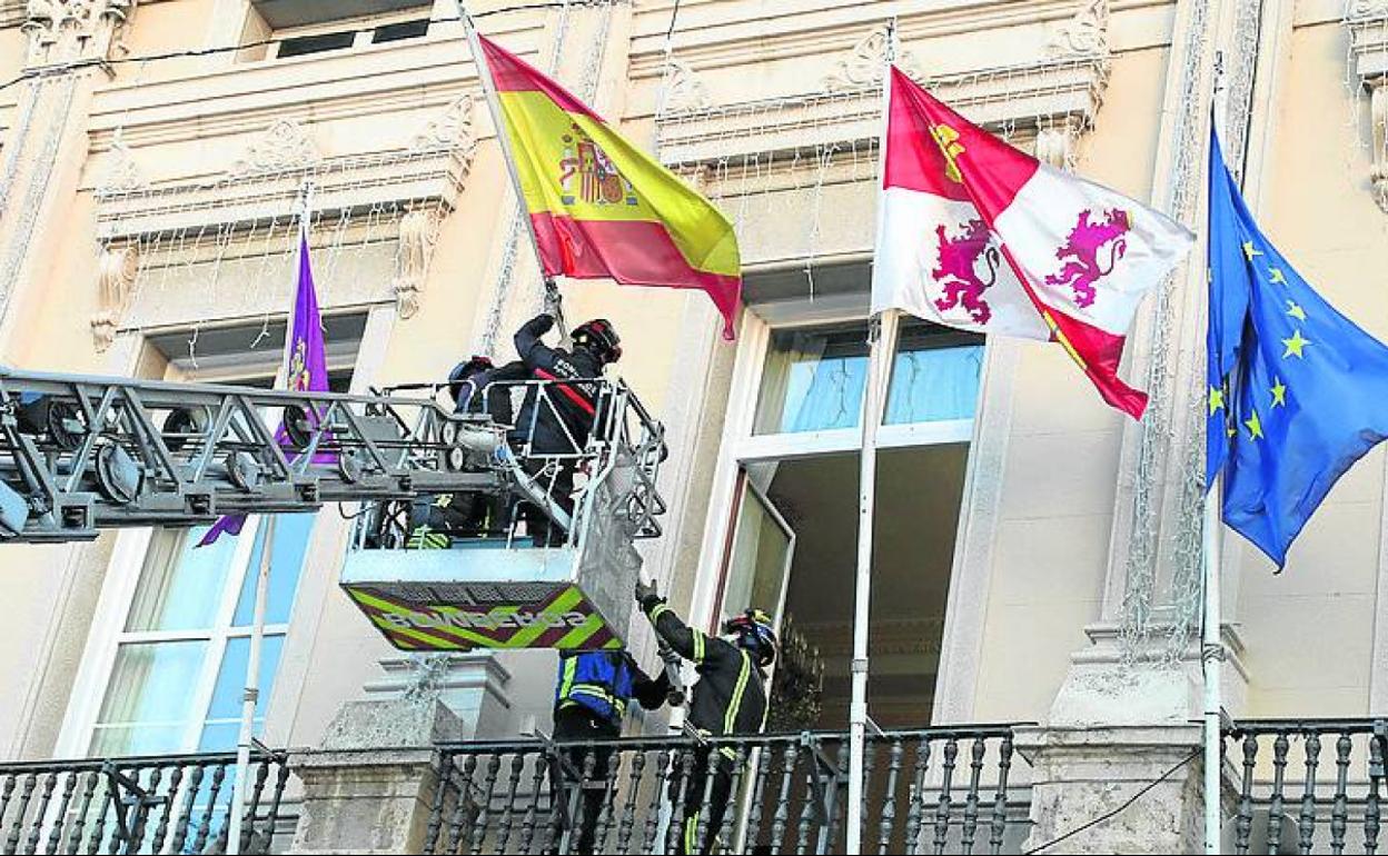 Los bomberos retiran las banderas del balcón del Ayuntamiento para la instalación de los fuegos artificiales que cerrarán la Cabalgata.