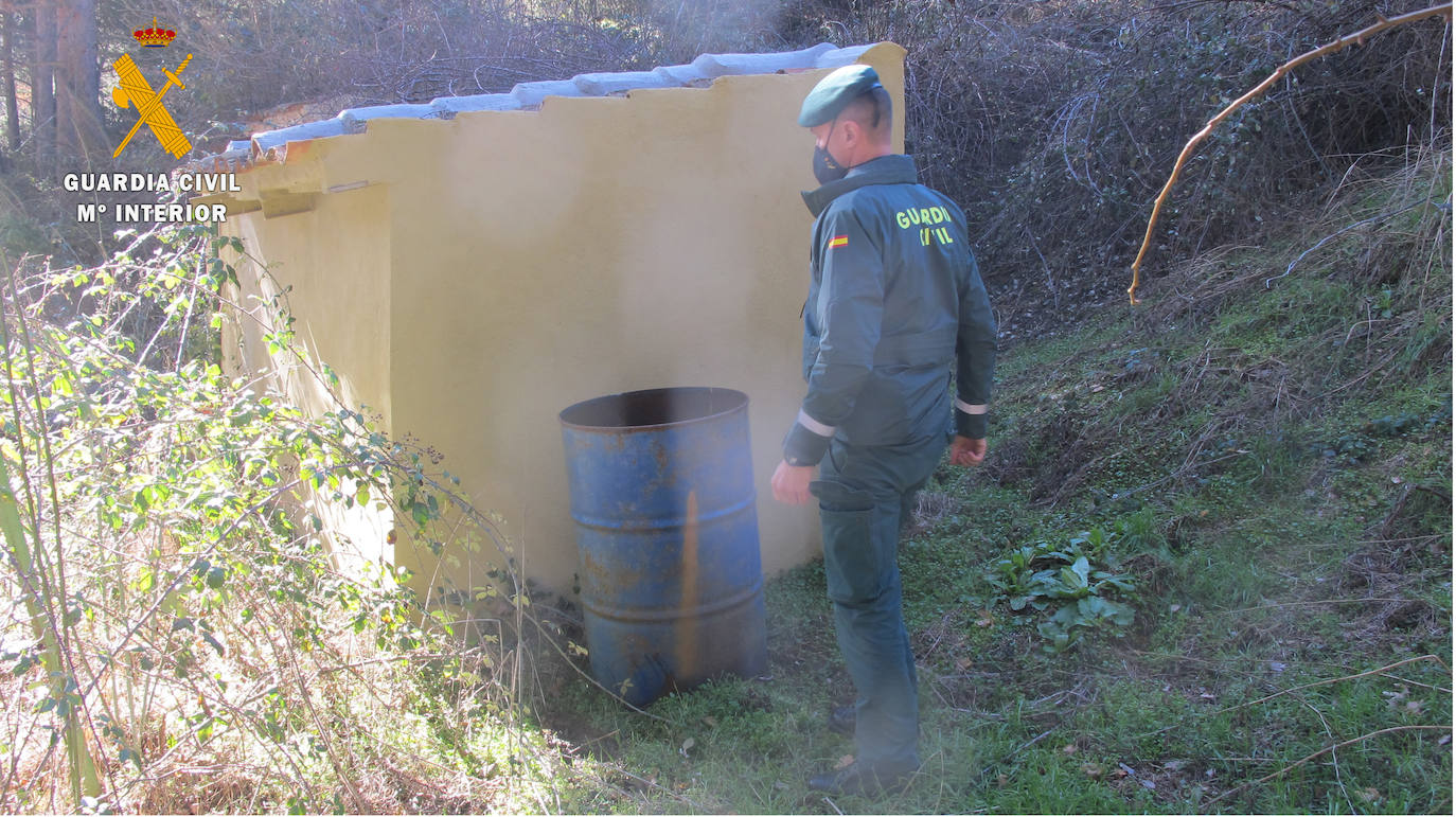 Un guardia civil inspecciona el bidón donde estaban los cuatro cachorros, tres de ellos muertos.