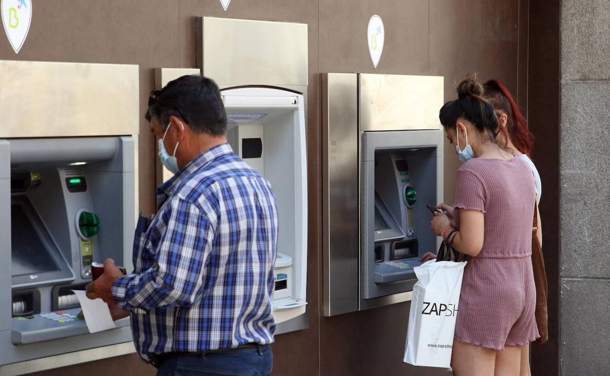 Varias personas sacan dinero en un cajero.