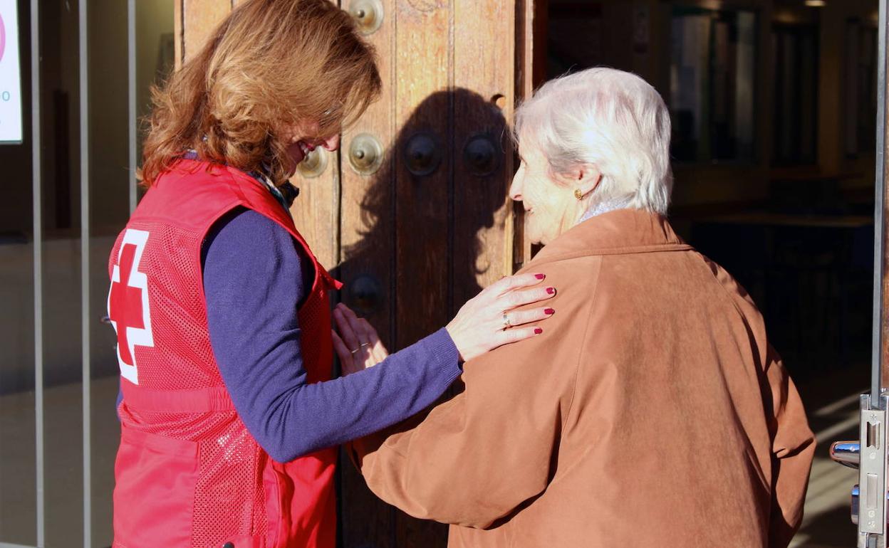 Una voluntaria de Cruz Roja acompaña a una mujer mayor. 