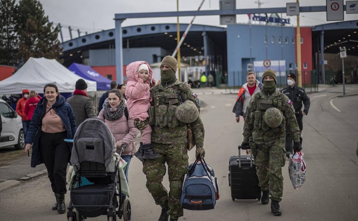 Soldados ayudan a pasar la frontera a civiles que huyen de la guerra. 