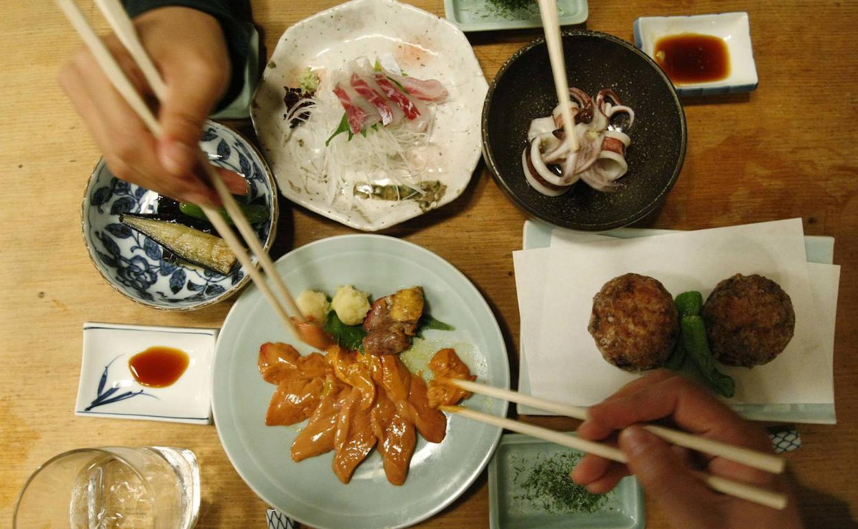 Gente compartiendo comida tradicional japonesa. 