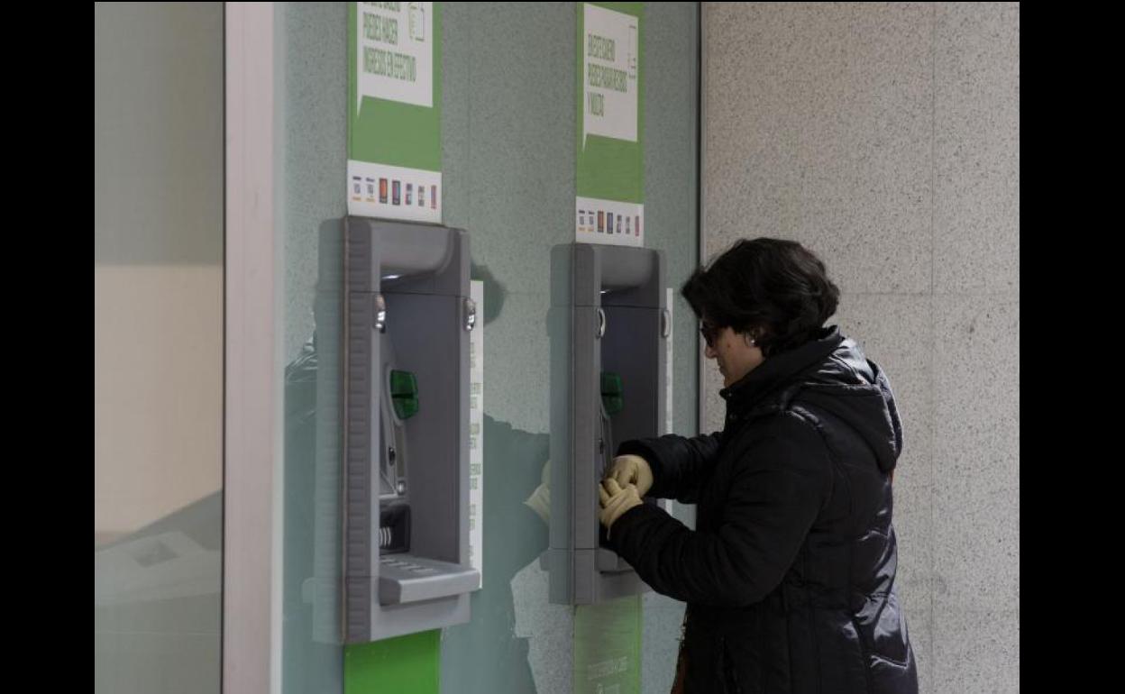 Una mujer saca dinero de un cajero autmático.
