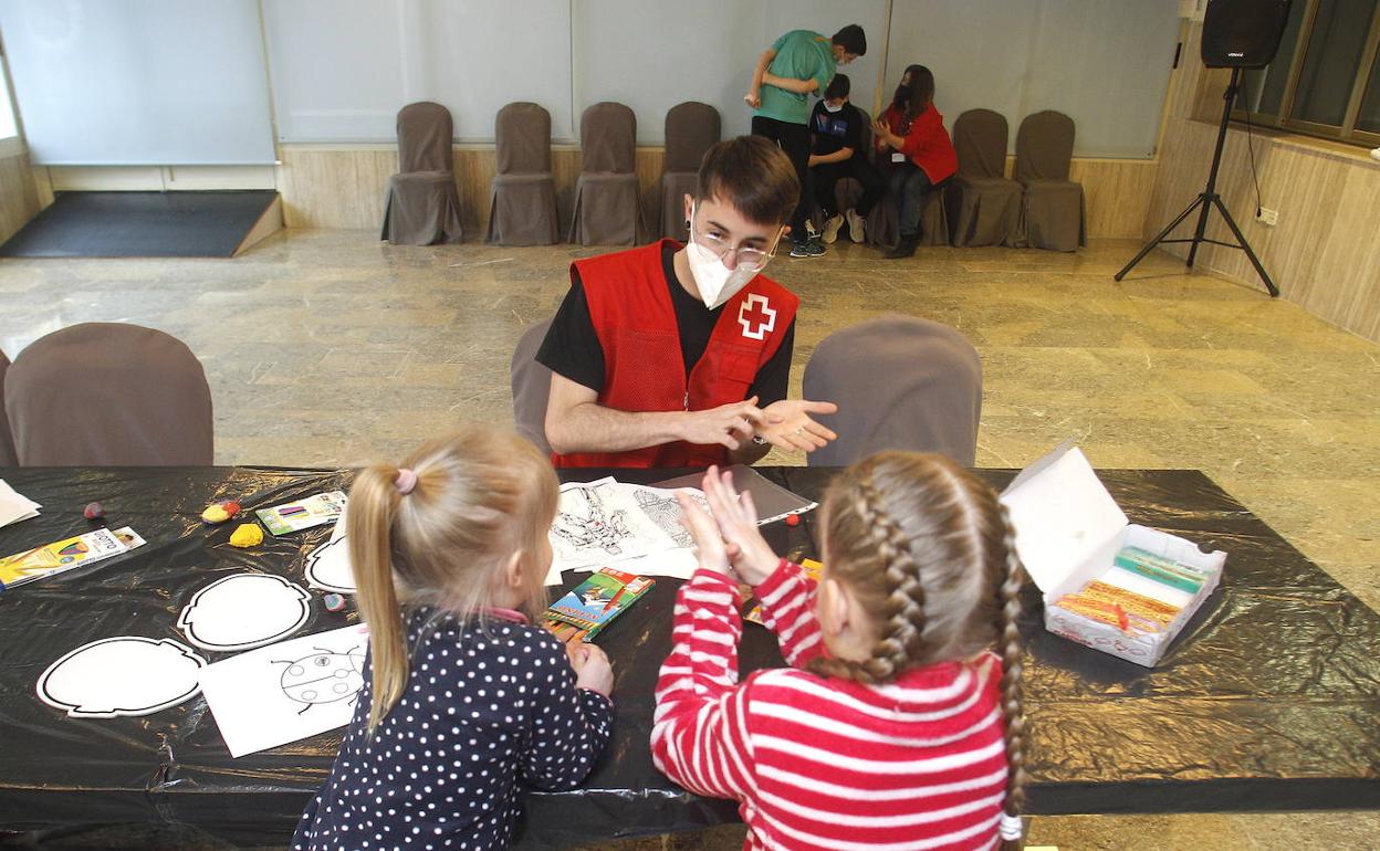 Un voluntario de Cruz Roja atiende a dos niños ucranianos refugiados en Alicante. 
