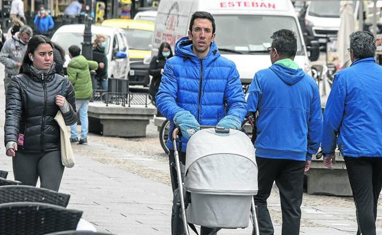 Un hombre pasea con el carrito de un bebé por una calle de Segovia. 