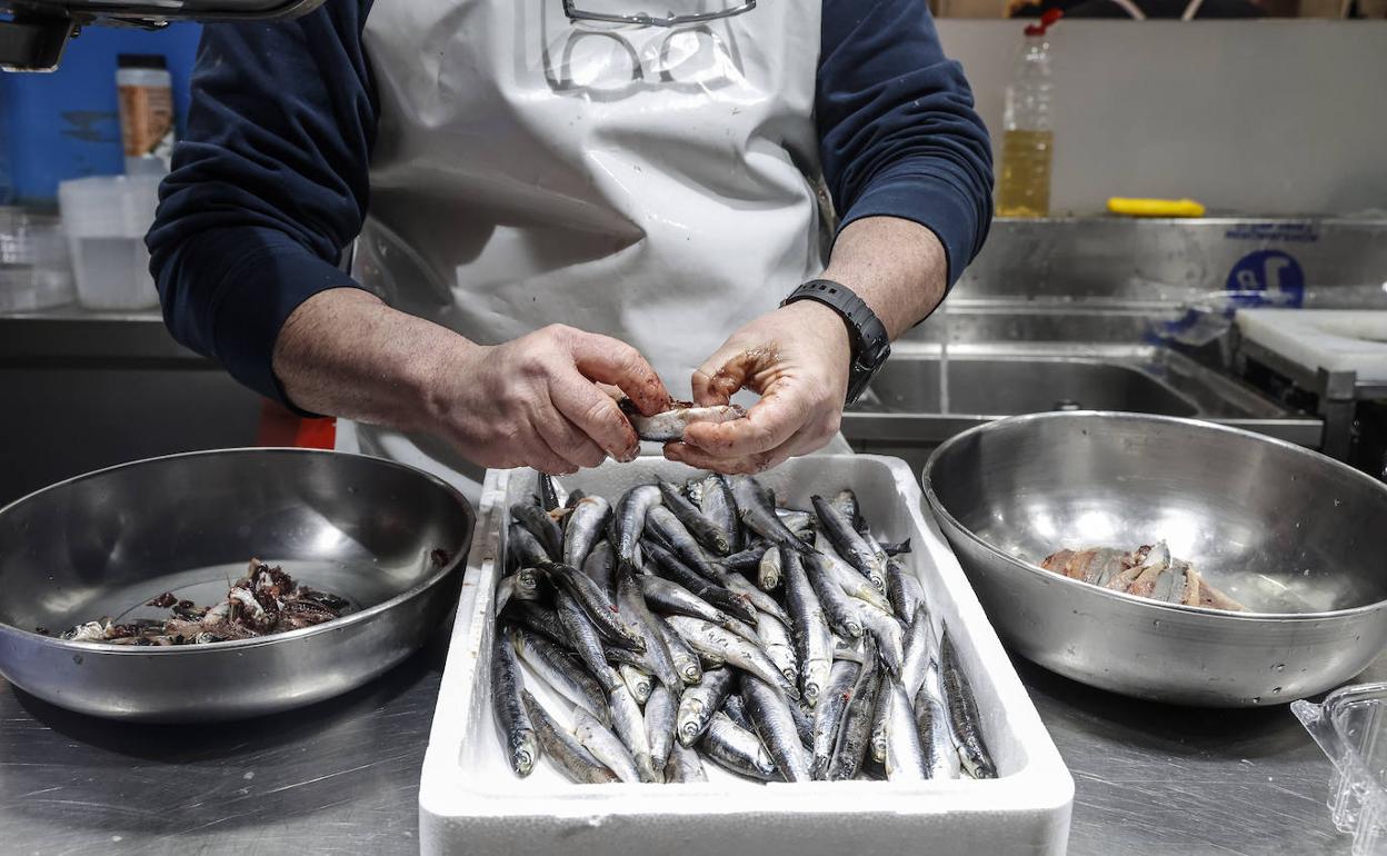 Un pescadero limpia el género en un puesto del mercado de Valencia. 