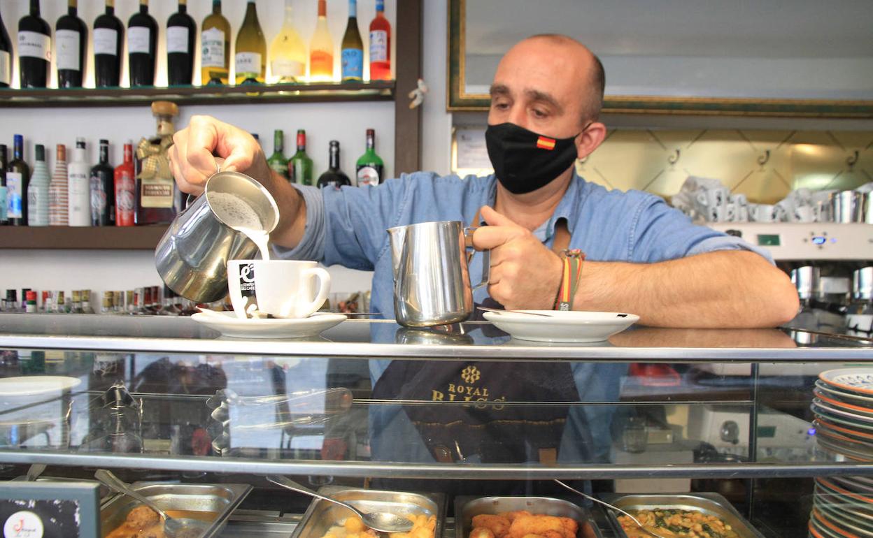 El camarero de un establecimiento de la ciudad prepara un café con leche para un cliente.