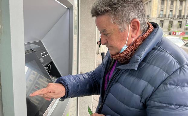 Carlos Alonso utiliza en un cajero su nueva tarjeta contactless tras una explicación de una empleada del banco. 