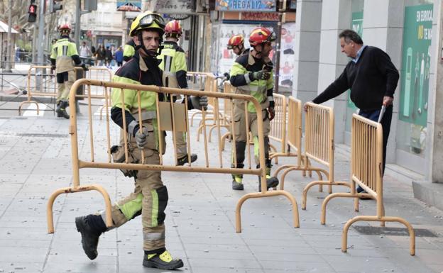 Un bombero retira una de las vallas; en el suelo, algunos de los cascotes que se han desprendido.