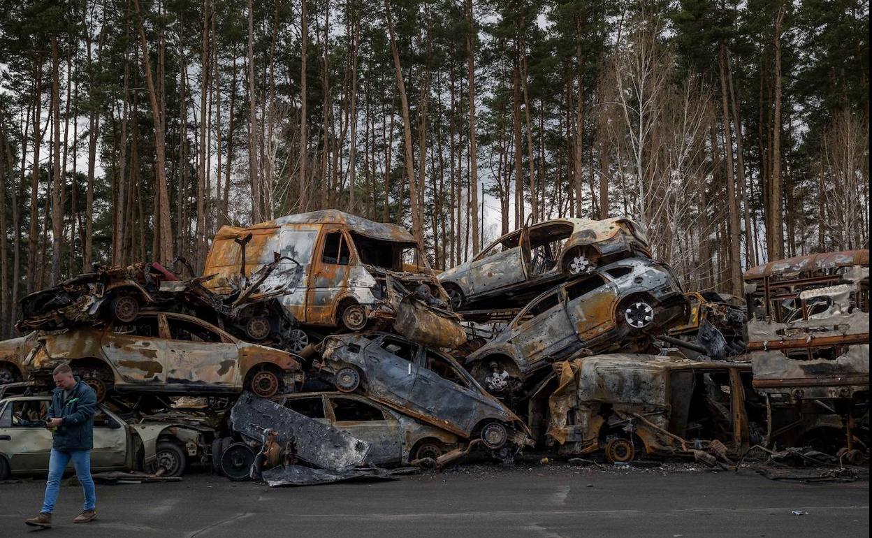 Un hombre pasa frente automóviles destrozados por los bombardeos en Irpin, región de Kiev (Ucrania).