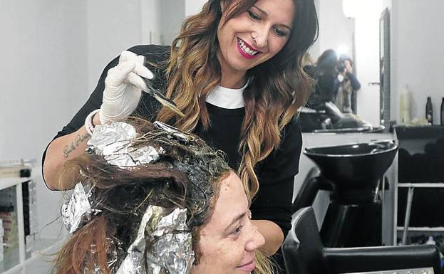 La peluquera Ainara Antolín tiñe el pelo a una clienta.