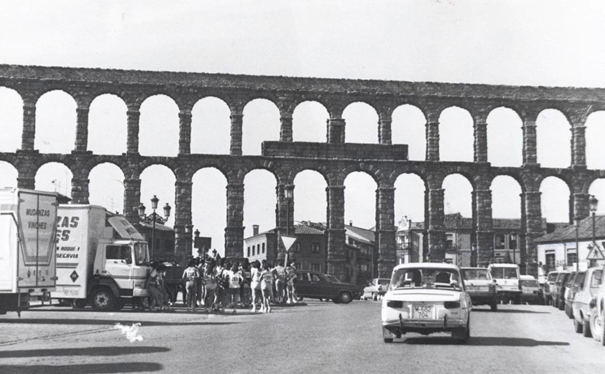 Fotografía antigua del Acueducto de Segovia, rodeado completamente de vehículos.