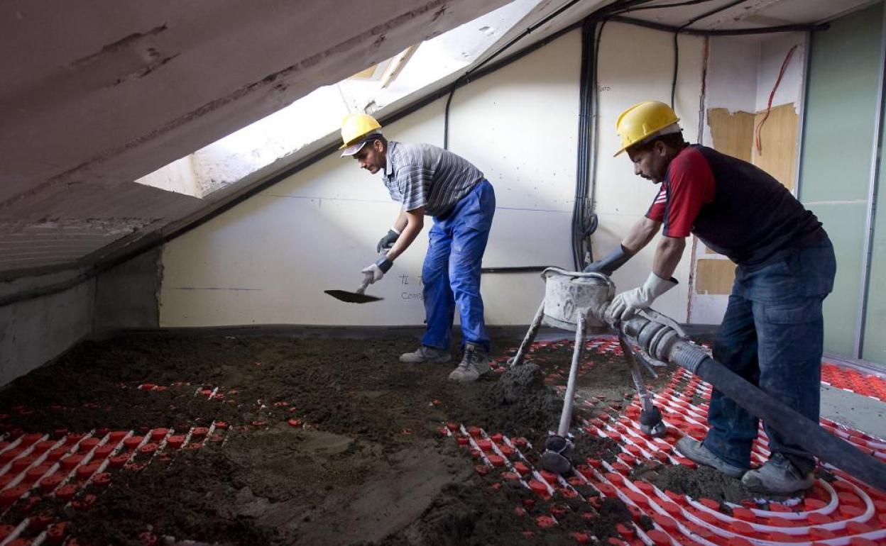 Dos hombres trabajan en la reforma de una vivienda.