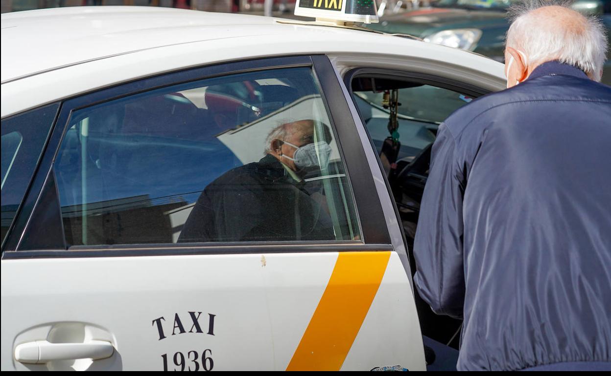 Una persona mayor con mascarillas coge un taxi el día que dejó ser obligario su uso. 