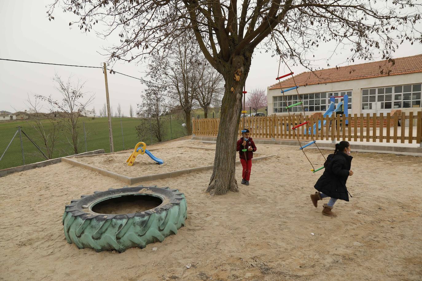 Dos niños juegan en los columpios del centro.