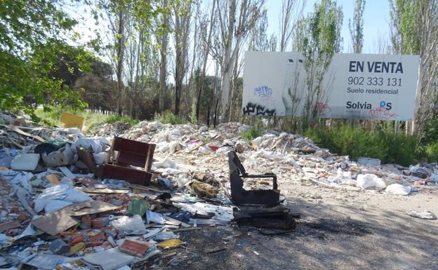 Escombros y sofás en torno a un camino de La Florida, junto al cartel de un solar en venta. 