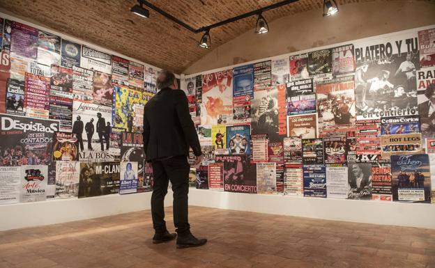 Una persona contempla carteles de conciertos que se incluyen en la exposición. 