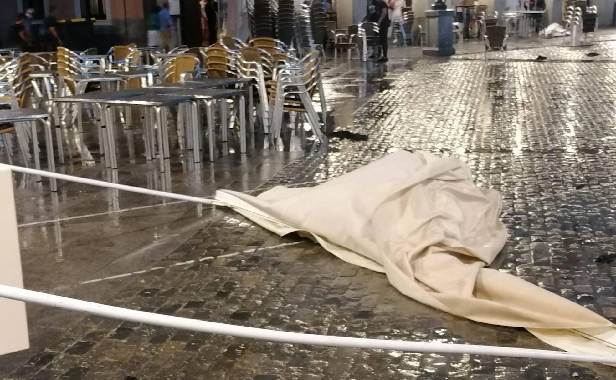 Toldo derribado por el viento en la noche de este sábado en Segovia y terrazas recogidas por la tormenta que descargaba en ese momento. 