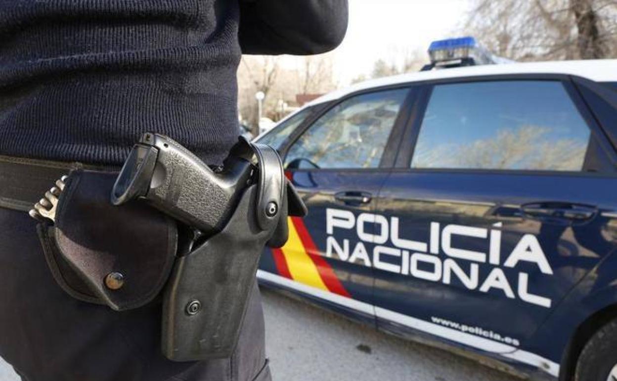 Un agente de la Policía Nacional junto al vehículo patrulla. 