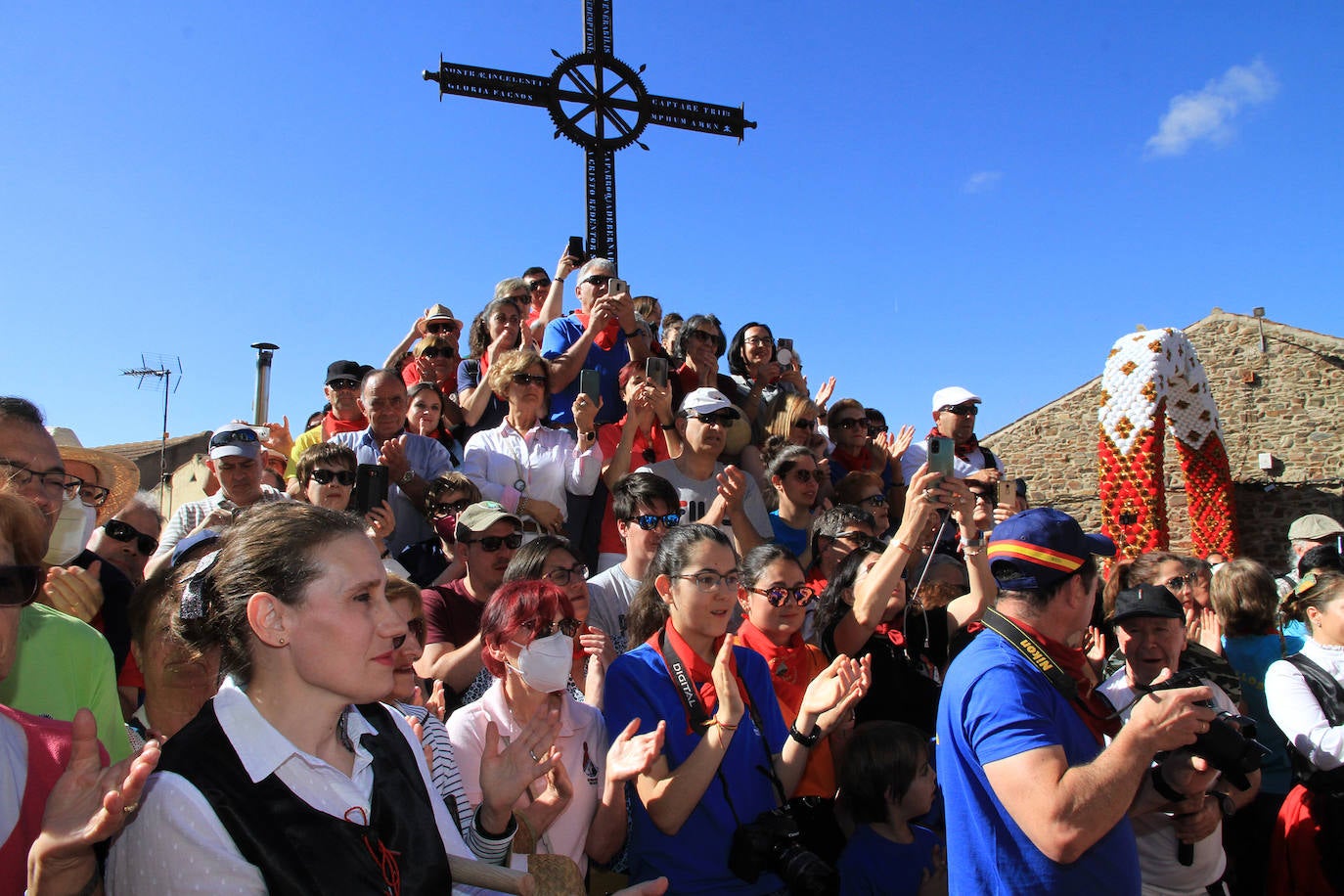 Los grupos de paloteo preceden el paso de la Virgen del Castillo por uno de los arcos de flores de papel en Bernardos. 