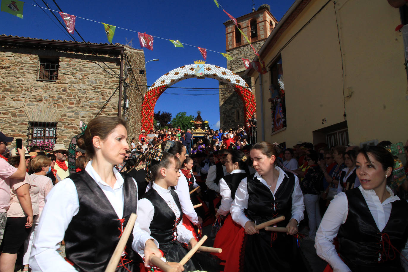 Los grupos de paloteo preceden el paso de la Virgen del Castillo por uno de los arcos de flores de papel en Bernardos. 