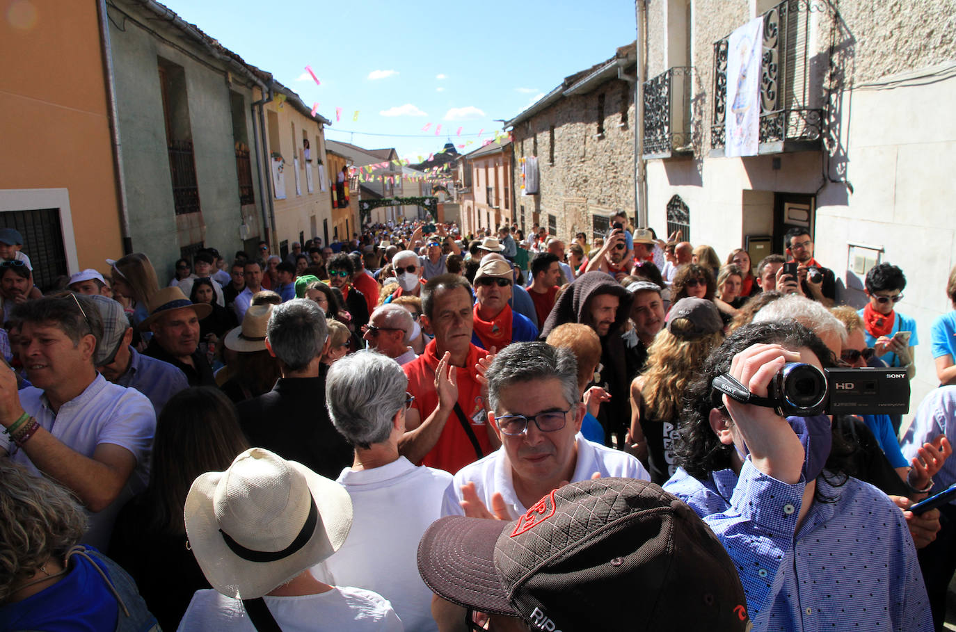 Los grupos de paloteo preceden el paso de la Virgen del Castillo por uno de los arcos de flores de papel en Bernardos. 