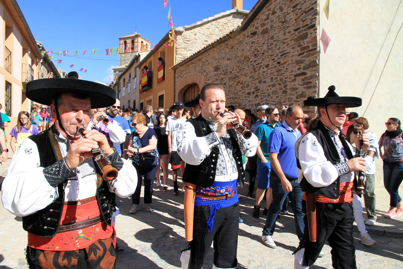 Los grupos de paloteo preceden el paso de la Virgen del Castillo por uno de los arcos de flores de papel en Bernardos. 