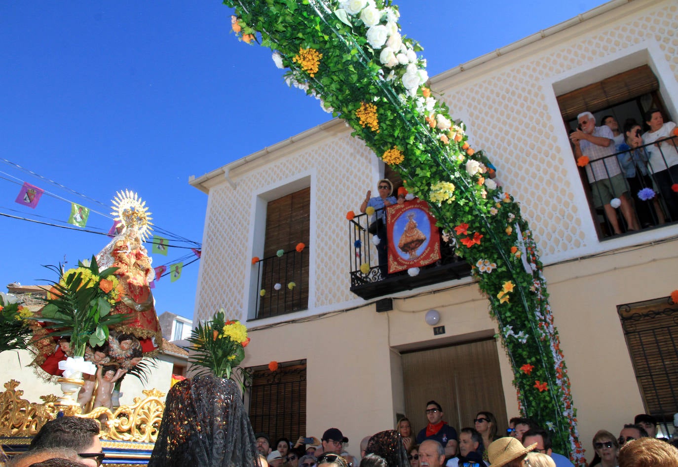 Los grupos de paloteo preceden el paso de la Virgen del Castillo por uno de los arcos de flores de papel en Bernardos. 