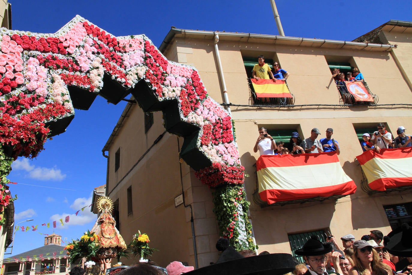 Los grupos de paloteo preceden el paso de la Virgen del Castillo por uno de los arcos de flores de papel en Bernardos. 