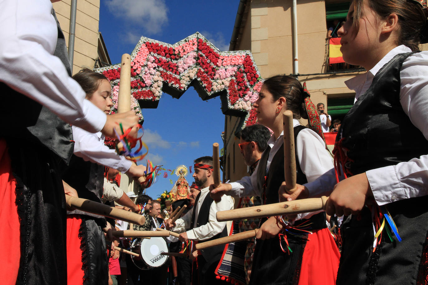 Los grupos de paloteo preceden el paso de la Virgen del Castillo por uno de los arcos de flores de papel en Bernardos. 