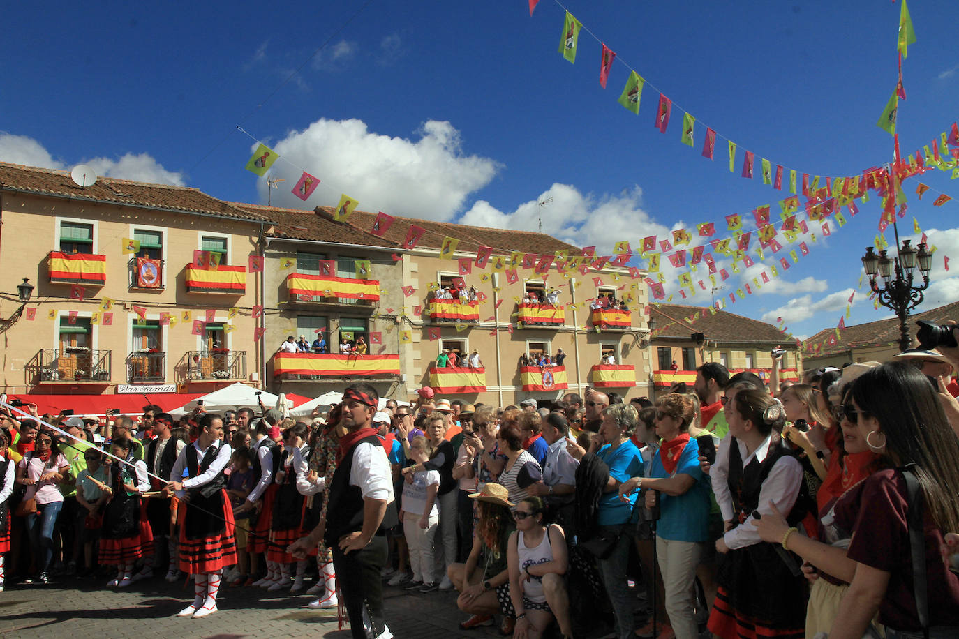 Los grupos de paloteo preceden el paso de la Virgen del Castillo por uno de los arcos de flores de papel en Bernardos. 