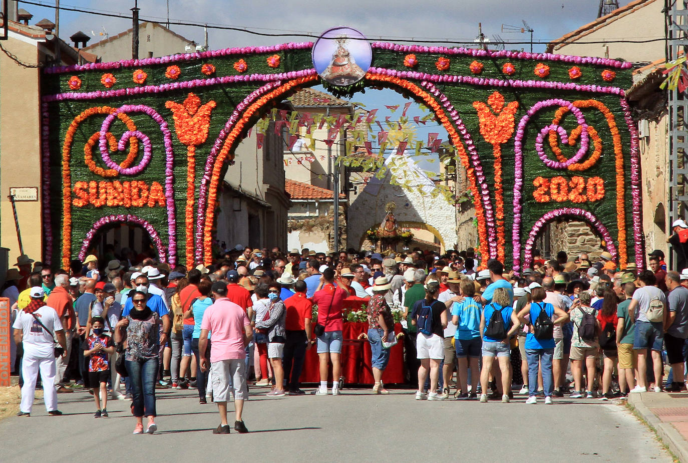 Los grupos de paloteo preceden el paso de la Virgen del Castillo por uno de los arcos de flores de papel en Bernardos. 