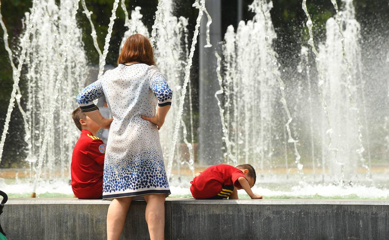 Una familia se refresca en la fuente de la plaza Zorrilla de Valladolid. 