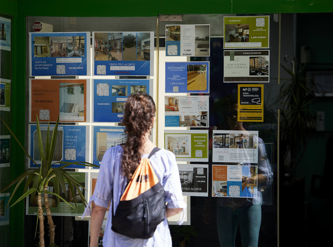 Una joven busca vivindas en alquiler en una inmobiliaria.